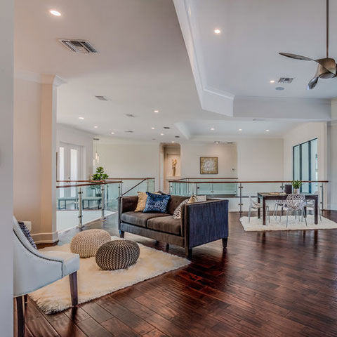 Open living remodel with glass railing and wood flooring